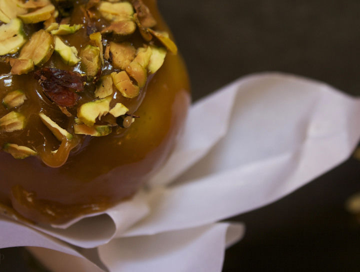 Manzanas cubiertas de caramelo con rodajas de pistache y hojuelas de maíz.