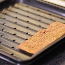 Precalentar el horno a 400 ° F (204 °C). Colocar las rebanadas de tocino sobre una charola para asar que tenga agujeros para que escurra la grasa del tocino. Hornear durante 12 minutos.