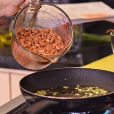 Añadir los frijoles y machacar con el machacador hasta obtener una mezcla firme. Continuar cociendo hasta obtener una pasta espesa que se pueda manipular. Apagar el fuego y dejar enfriar.