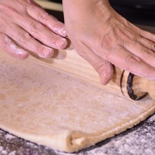 Extender la pasta de hojaldre hasta que quede bien delgado utilizando un rodillo sobre una mesa enharinada.