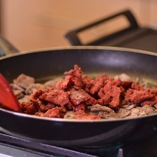 Regresar el bistec picado al sartén, agregar el chorizo y revolver todo.