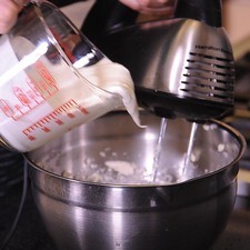 Añadir la crema poco a poco sin dejar de batir. Parar y bajar la mezcla de los lados, continuar batiendo hasta que la mezcla esté bien integrada.