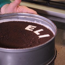 Espolvorear las galletas molidas sobre toda la superficie. Retirar las letras con una pinza.