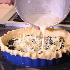 Colocar las espinacas y el queso gruyere bien esparcidos sobre la masa base en el molde para pay. Agregar la mezcla de huevo batido.