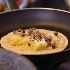 Esparcir el queso rallado y los champiñones. Doblar la tortilla a la mitad, calentar por 2 a 3 minutos.