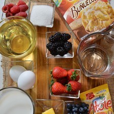 Ingredientes para decorar: 1/4 taza de frambuesas 1/4 taza de mora azul 1/4 taza de fresas 1/4 taza de zarzamora Ingredientes para crema pastelera: 1 sobre de harina para atole Tres Estrellas 20 gramos de mantequilla 125 gramos de azúcar blanca 2 piezas de huevo 250 mililitros de leche de vaca Ingredientes para buñuelos: azúcar blanca al gusto aceite de canola al gusto 160 mililitros de agua caliente 2 tazas de harina para buñuelos Tres Estrellas