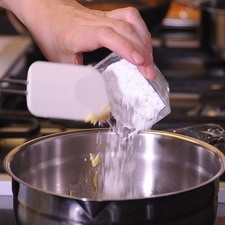 Para preparar los buñuelos, colocar en un tazón la harina para buñuelos. Añadir con mucho cuidado el agua hirviendo y revolver con la ayuda de la pala de madera. Amasar 3 o 4 minutos hasta que la mezcla este uniforme.
