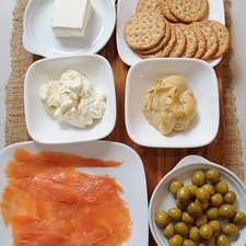 lonchas de salmón al gusto palillos al gusto galletas al gusto 95 gramos de queso crema 1/2 taza de jocoque 1/2 taza de humus 6 piezas de mini elotes 15 piezas de aceituna rellena