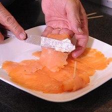 Para preparar los rollitos, colocar la lonja de salmón sobre la tabla para picar y añadir un poco de queso crema con la ayuda de un cuchillo y enrollamos de un extremo al otro para formar el rollito.