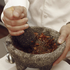 Cuando el chile empieza a cambia de color, reservar el aceite y pasar el chile y el ajo a un molcajete, agregar sal. Moler bien con el molcajete. Agregar el aceite al molcajete e integrarlo con la pasta de chile y ajo.