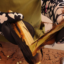 Pelar los elotes con cuidado utilizando guantes térmicos, retirando toda la cáscara quemada y los pelos. Introducir un tenedor o palo de madera para sostener el elote.