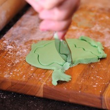 Tomar un pedazo de la masa y agregar colorante y sobre una hoja de papel encerado amasar y cortar la figura.