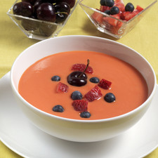 Picar las fresas en cuartos. Servir en un platón hondo la sopa de frutas y adornar con las fresas, zarzamoras y frambuesas.