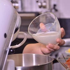 Agregar poco a poco la leche, esencia de vainilla, huevos y batir.