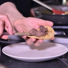 Servir la tostada untamos frijoles refritos.