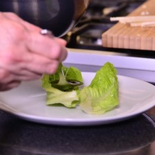 Colocar una hoja de lechuga mini romaine en un plato, llenar con un poco del aderezo y colocar encima la brocheta.