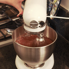 Para preparar el pastel de chocolate, batir harina para pastel, las dos cucharadas de mantequilla derretida, los tres huevos, la lata de leche evaporada y el aceite en la batidora, comenzando por una velocidad baja y subiendo hasta deshacer todos los grumos y obtener una mezcla uniforme.