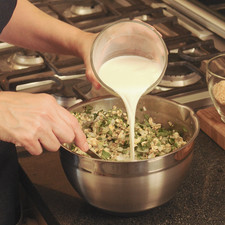 Añadir la leche poco a poco, mezclando constantemente. Puede requerir un poco más o un poco menos de leche, se debe agregar leche hasta que la mezcla quede solamente con un poco de sobrante de leche. Agregar un poco de pan molido y revolver hasta obtener la consistencia de una pasta espesa.