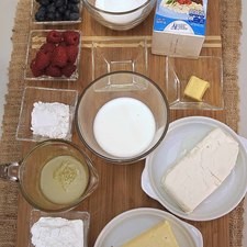 Ingredientes para toda la receta 1/2 taza de Claras de Huevo San Juan 190 gramos de queso crema 250 gramos de queso fresco 1/2 taza de leche de vaca 1/3 taza de maicena (fécula de maíz) 1/2 taza de azúcar blanca 1 cucharita de esencia de vainilla 2 cucharadas de mantequilla 2 cucharadas de harina de trigo Ingredientes para decorar 1/4 taza de moras azules 1/4 taza de frambuesas