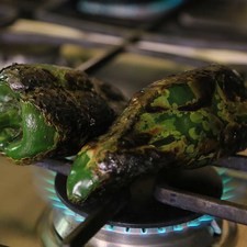 Tostar los chiles sobre la lumbre directa de la hornilla dando vuelta con una pinza hasta que se vean negros por todas partes.