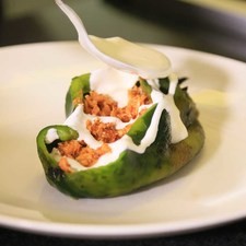 Colocar un chile en un plato y añadir un poco de crema sobre cada chile.