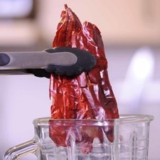 Colocar en el vaso de la licuadora las pieles de los chiles, el diente de ajo.
