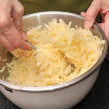 Rallar la cebolla. Revolver en un tazón la cebolla con las papas ralladas, sal de ajo y pimienta blanca.