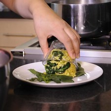 Colocar una hoja de espinaca y hacer un volcán con la mezcla de arroz.