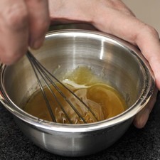 Preparar un aderezo colocando en un tazón el aceite de oliva, el vinagre balsámico, la sal de mar y la pimienta negra. Batir utilizando un batidor de globo hasta obtener una mezcla homogénea.