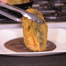 Calentar el caldo de frijol, hacer un espejo en un plato y colocar el chile capeado encima y decorar con un poco de epazote picado.