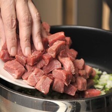 Acitornar la cebolla en aceite de oliva hasta que quede transparente pero no dorada. Añadir el chile serrano (opcional) menear con la pala para que se acitrone unos segundos. Agregar la carne de res en trozos pequeños y la pimienta y continuar moviendo hasta que quede cocida pero no muy dorada.