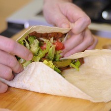 Envolver la tortilla doblando primero hacia el centro la parte de abajo y después enrollando los lados.