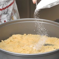 Colocar las migajas en un molde para pastel, mezclar con el azúcar.
