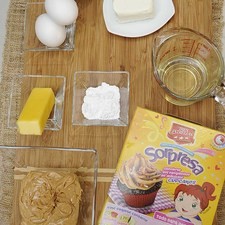 Ingredientes para panquecitos: 400 gramos de harina para panquecitos sorpresa sabor chocolate tres estrellas Nuevo granillo de colores al gusto Nuevo 2 piezas de huevo 1/2 taza de agua 1/3 taza de aceite vegetal comestible 12 piezas de capacillos para cupcake Ingredientes para betún: 60 gramos de mantequilla 90 gramos de queso crema 2 cucharadas de azúcar glass (pulverizada) 280 gramos de mantequilla de cacahuate