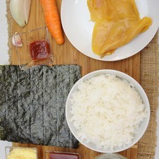 Ingredientes para arroz frito 3 tazas de arroz al vapor 1 pieza de milanesa de pollo 1 pieza de zanahoria 1 diente de ajo 1/4 pieza de cebolla blanca 1 cucharada de salsa catsup sal al gusto aceite vegetal comestible al gusto papel plástico adherente al gusto Ingredientes para decorar 3 piezas de huevo 1 pieza de alga nori (seca) mayonesa al gusto salsa catsup al gusto palillos al gusto