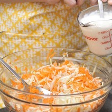 Mezclar la leche y la crema en un tazón y sazonar con sal al gusto. Agregar la col y la zanahoira ralladas y mezclar bien.