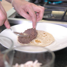 Untar cada tortilla con una capa de frijoles sólo en la mitad de la tortilla.