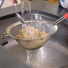 Preparar la quinoa, colocar la quinoa en un colador bajo el chorro de agua, mover con la mano o una cuchara para que se limpie bien.