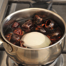 Lavar y desvenar los chiles cascabel y retirar todas las semillas y el rabo. Ponerlos a hervir en una olla pequeña con agua junto con un diente de ajo y ¼ de la cebolla durante 5 minutos. Dejar enfriar, moler en la licuadora con muy poca agua. Sofreír la salsa en una sartén abierta con un poco de aceite de canola durante un par de minutos y sazonar con sal al gusto.