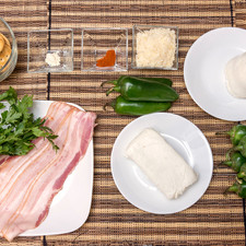 Ingredientes para receta 10 piezas de chile jalapeño 190 gramos de queso crema 200 gramos de queso mozzarella 1/4 taza de queso parmesano rallado 1/4 cucharita de ajo en polvo 1/4 cucharita de paprika 4 ramas de perejil fresco 10 piezas de galleta salada 10 rebanadas de tocino 1 pieza de bolsa de plástico
