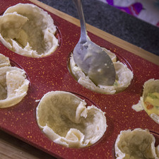Agregar un poco de la mezcla a cada uno de los moldes con las tortillas de harina hasta llenar ¾ partes del molde.