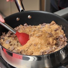 Agregar el pan molido, mover para integrar bien. Añadir las menudencias picadas y el azúcar a la mezcla de pan, y continuar cociendo 3 minutos más sin dejar de mover.