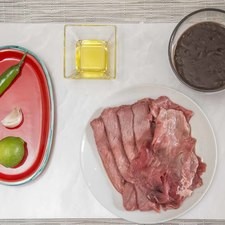 Ingredientes para receta 4 piezas de filete de res 1 pieza de chile serrano 1 diente de ajo pimienta negra molida al gusto 1 pieza de limón 2 cucharadas de aceite de oliva sal al gusto 1 taza de frijoles refritos 1/2 cucharita de mejorana