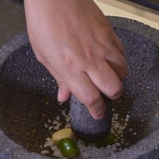 Colocar en el molcajete el diente de ajo, chile serrano, mejorana y sal. Moler con la piedra hasta obtener una pasta.