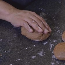 Amasar cada porción de masa con las manos en forma circular de afuera hacia adentro para formar la bola.