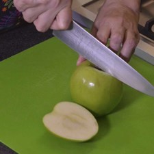 Colocar las manzanas sobre la tabla para picar y cortar cada una en dos partes, descartando el corazón y semillas.