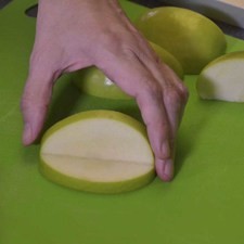 Tomar la mitad de cada manzana y cortar en dos partes. Hacer un corte triangular a cada cuarto de manzana sin cortar totalmente, esto permitirá obtener la figura de una boca.