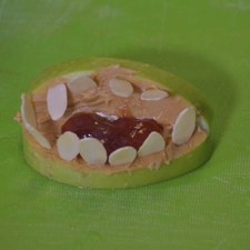 Coloca unas láminas de almendra en los dos lados de la manzana para formar los dientes.