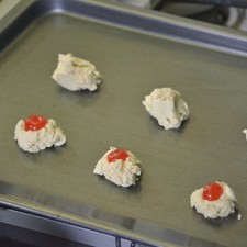 Colocar la mitad de una cereza sobre cada chopito. Hornear durante 15 a 17 minutos a 350°F (175°C) o hasta que la base de las galletas se comience a ver dorada. Retirar del horno y dejar enfriar.