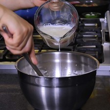 Añadir leche poco a poco y batir hasta obtener una mezcla espesa sin grumos.